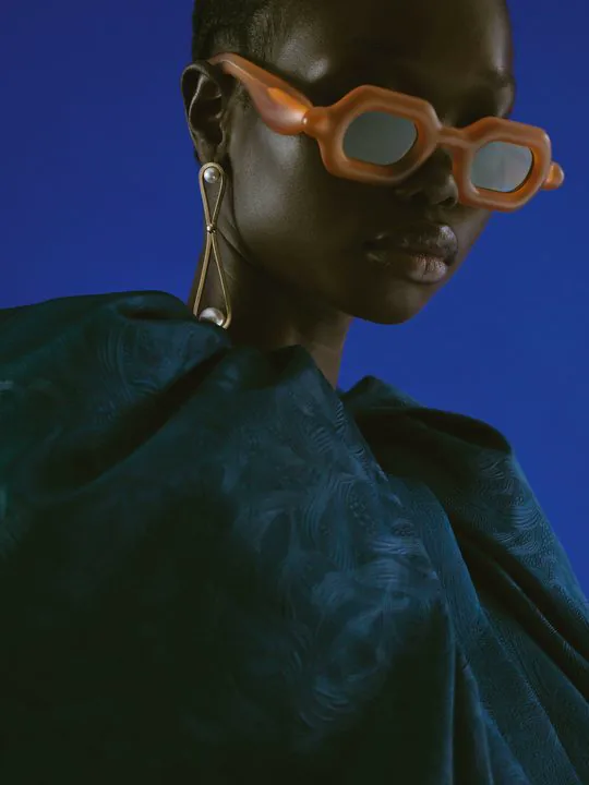 Paloceras editorial — model in orange frames on a blue backdrop